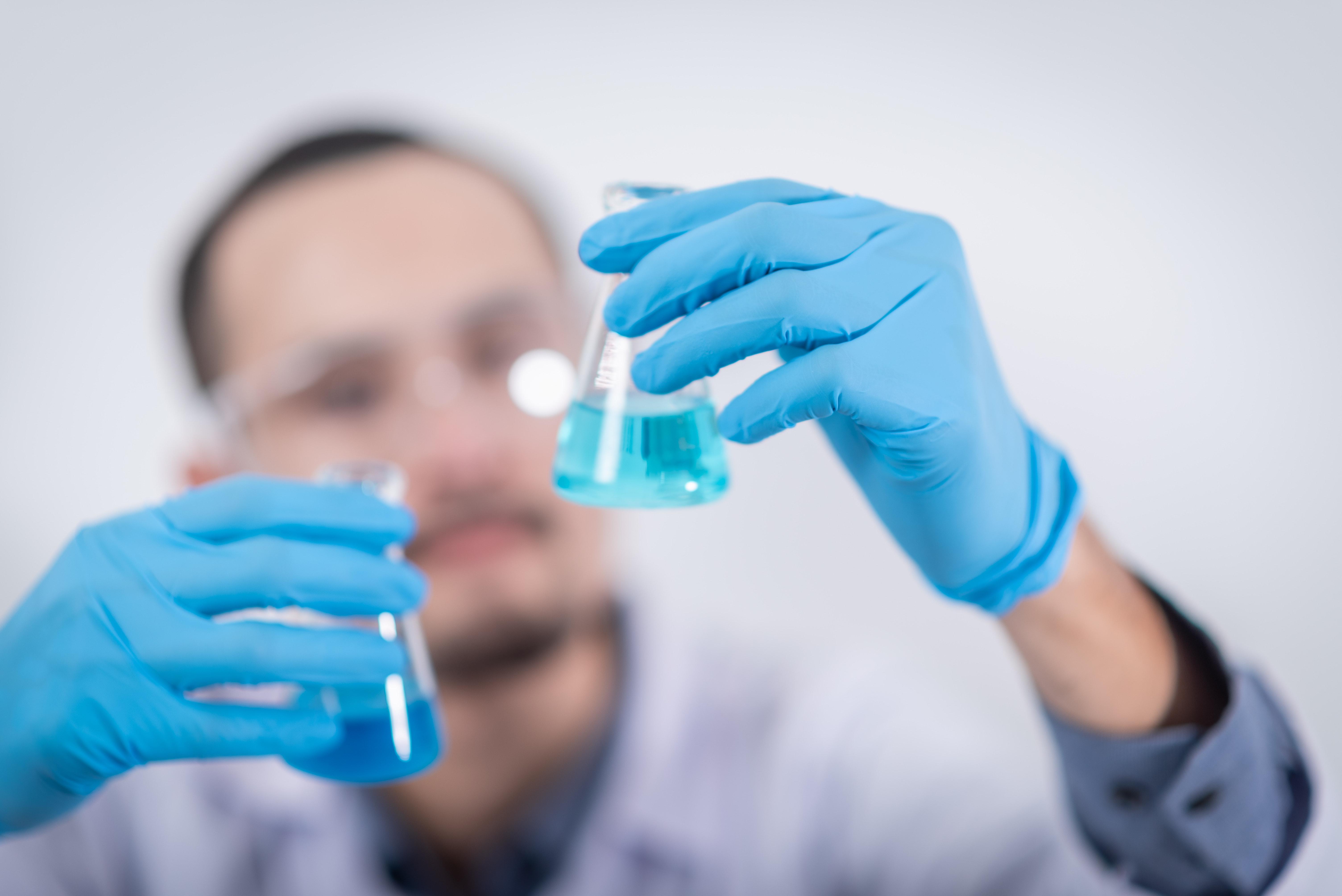 A scientist mixing chemicals in flasks